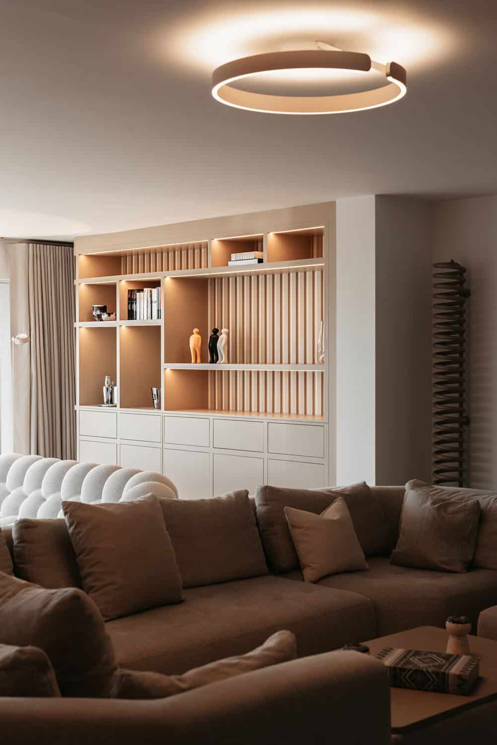 Living room with bespoke lit shelving and a ring pendant light