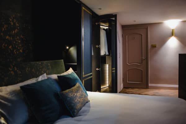 Bedroom with dark joinery, gold detailing and a walk-in wardrobe