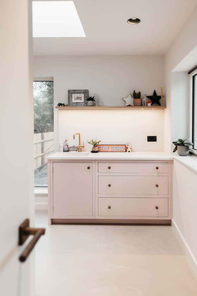 Pale pink utility room with brass tap and a skylight