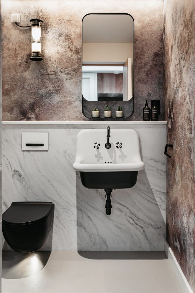 Cloakroom with marble panelling, a wall-hung basin and a black WC