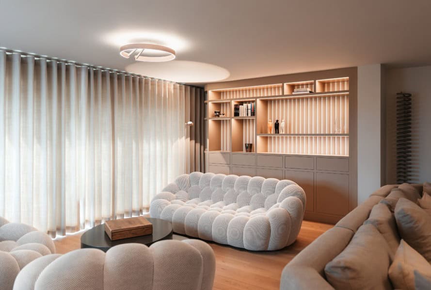Duneside living room with lit bespoke shelving and curved sofas